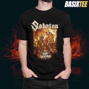 Op de afbeelding: Zwart T-shirt met de bandnaam "Sabaton" in een gestileerd lettertype boven een afbeelding van soldaten in de strijd. De tekst "Heroes of the Great War" staat eronder. De merknaam "BASIXTEE" staat rechtsboven.
