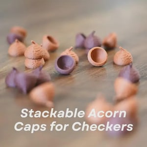 May include: A collection of stackable acorn caps in shades of brown and purple, designed for use in a checkers game. The image shows several caps scattered on a wooden surface, with the text "Stackable Acorn Caps for Checkers" in white.