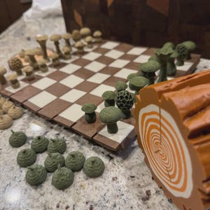 May include: A unique chess set with mushroom-shaped pieces in shades of green and tan. The board features a brown and cream checkered pattern. A decorative log slice is on the side, adding to the forest theme.