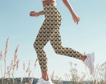 May include: Tan leggings with a repeating pattern of black dog faces wearing sunglasses. The leggings are worn with a white crop top and white athletic shoes. The person is running outside on a sunny day.