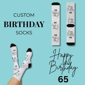 Pode incluir: Meias de aniversário brancas com calcanhares e dedos pretos. As meias apresentam o texto "Happy Birthday 65" em fonte cursiva. As palavras "Custom Birthday Socks" também são exibidas.