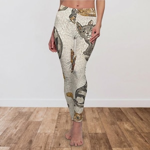 May include: White leggings with a mosaic-style pattern featuring various cat illustrations in shades of gray, brown, and gold. The leggings have a high waist and a fitted design, suitable for athletic activities or casual wear.