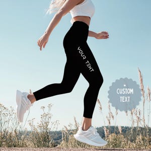 May include: Black leggings with the text "YOUR TEXT" printed vertically on the left leg. The leggings are worn with a white top and white athletic shoes. A blue and gray circle with the text "CUSTOM TEXT" is in the lower right corner.