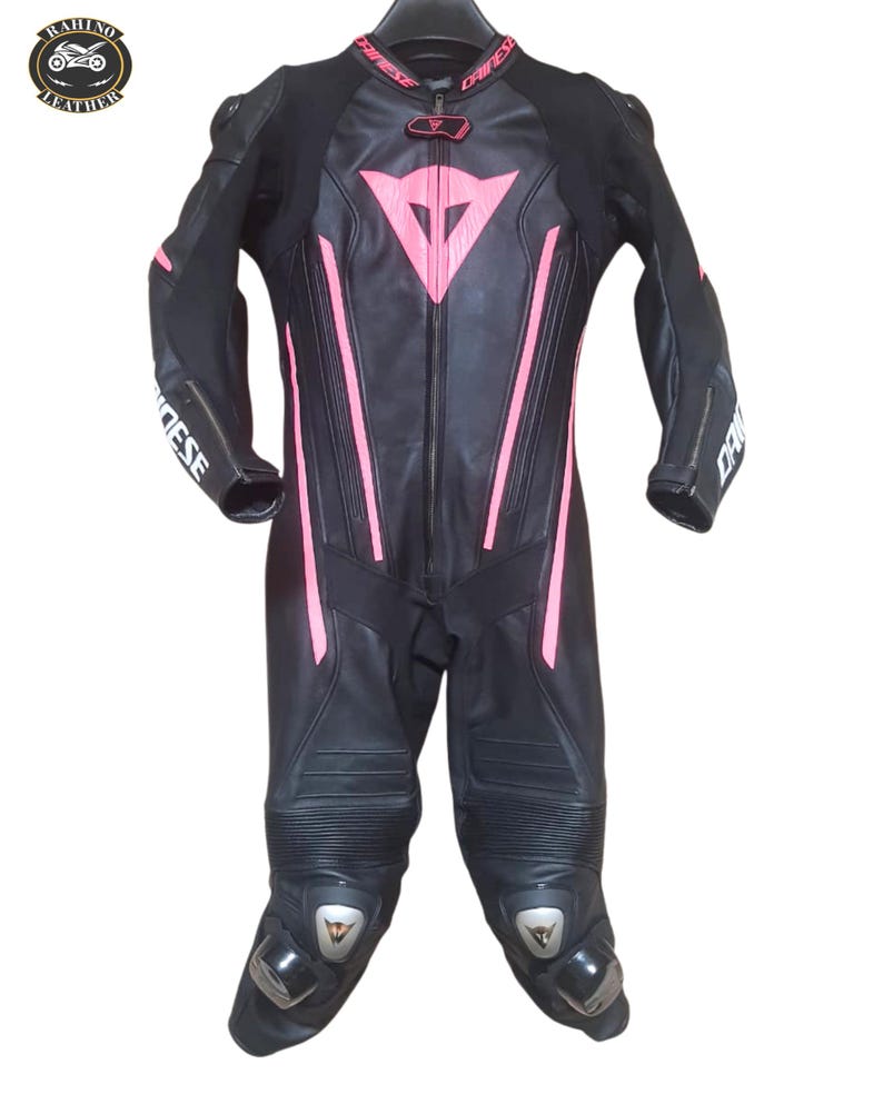 May include: Black leather motorcycle racing suit with pink detailing. Includes a full-length zip, protective padding on the knees and elbows, and the brand name "Dainese" on the sleeves. The suit is designed for speed and protection.