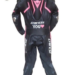 May include: Black leather motorcycle suit with pink detailing and the text "DAINESE YOU". The suit features silver elbow protectors and the "RAHINO LEATHER" logo. This one-piece suit is designed for motorcycle use.