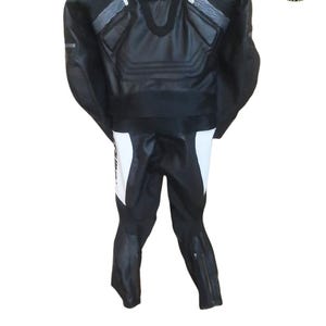 Puede incluir: Una taza de cer&aacute;mica blanca con asa negra y el texto "But First, Coffee" en negrita negra. La taza se encuentra sobre un fondo borroso, sugiriendo un ambiente acogedor.