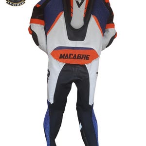 May include: A motorcycle racing suit in black, white, blue, and orange. The suit has a streamlined design with the word "MACABRE" across the back. The suit features a logo on the upper left and is designed for protection and speed.