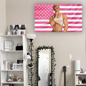 May include: A large rectangular wall art piece featuring a muscular male figure in a white tank top, set against a pink and white American flag design. The artwork is displayed above a mirror and a guitar.