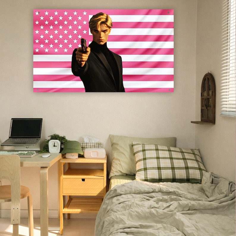 May include: A rectangular wall tapestry featuring a stylized illustration of a person with blonde hair wearing a black turtleneck and blazer, holding a handgun. The background is a pink and white version of the American flag with stars and stripes.