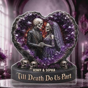 Op de afbeelding: Een decoratief beeldje met twee skeletten in trouwkleding in een hartvormige paarse amethist geode. De voet toont de tekst "HENRY & SOPHIA" en "Till Death Do Us Part" met kleine schedels en rozen als decoratieve accenten.