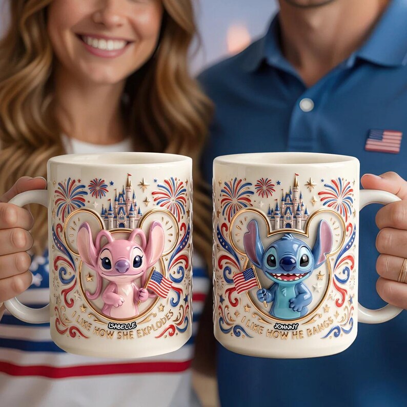 May include: Two white ceramic mugs featuring embossed 3D characters. The left mug shows a pink alien holding a small American flag with the text 'ISABELLE' and 'I LIKE HOW SHE EXPLODES'. The right mug shows a blue alien with 'JOHNNY' and 'I LIKE HOW HE BANGS'.