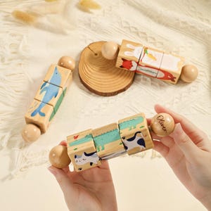 May include: Wooden animal block puzzles with rounded end pieces. One puzzle features a blue dolphin, another a fox and rabbit, and a third with a cat, crocodile, and cow. The end piece of one puzzle is engraved with the name "Oliver".