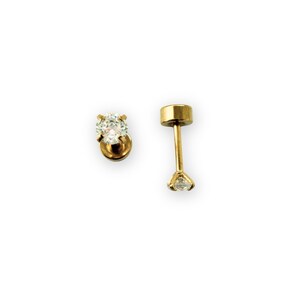 May include: Two gold-colored stud earrings with clear, round gemstones. One earring is a complete stud, while the other is disassembled, showing the post and backing. The earrings are set against a white background.