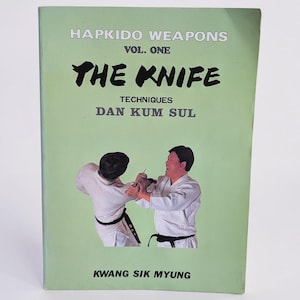 Könnte beinhalten: Ein hellgrünes Buch mit dem Titel Hapkido Weapons Vol. One The Knife Techniques Dan Kum Sul von Kwang Sik Myung. Das Cover zeigt ein Foto von zwei Personen in weißen Kampfkunstuniformen, die Messerabwehrtechniken üben.