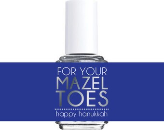 May include: A clear glass bottle of nail polish with a white cap. The bottle has a blue label with the text "FOR YOUR MAZEL TOES happy hanukkah" in silver lettering.