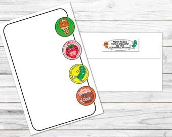 May include: White stationery with colorful cartoon stickers featuring an ice cream cone, strawberry, pickle, and a mug of root beer. An envelope with an address label is also present, with the text "NOAH REESE TRAIL'S END CAMP".