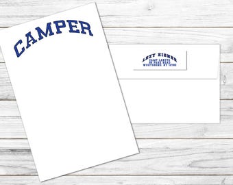 May include: White stationery set featuring a sheet of paper with the word "CAMPER" in blue arched text and a matching envelope. The envelope has a blue printed return address.