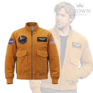 Puede incluir: Chaqueta bomber de pana marrón dorado con cremallera, dos bolsillos delanteros y puños y dobladillo acanalados. Parches con el logo de la NASA, la bandera estadounidense y un emblema militar. Diseño clásico y vintage.