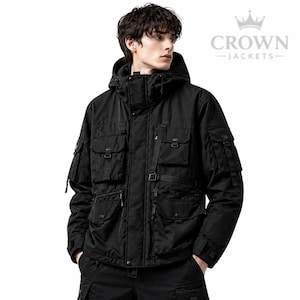 Peut inclure: Veste noire à capuche avec plusieurs poches et une fermeture éclair. La veste présente un col haut et un logo qui se lit "CROWN - JACKETS". La veste est conçue avec plusieurs poches et des sangles.