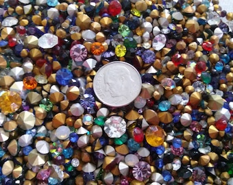 May include: A large assortment of colorful rhinestones and gold-toned metal studs. A US dime is included for scale.