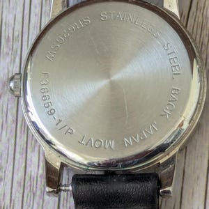 Pu&ograve; includere: Primo piano del retro di un orologio da polso con cinturino in pelle nera. Il retro dell'orologio &egrave; argentato con le scritte "STAINLESS STEEL BACK" e "JAPAN MOVT" incise. La cassa dell'orologio &egrave; argentata.