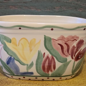 Peut inclure: Pot de fleurs en céramique blanche avec des tulipes peintes à la main en jaune, rose et bordeaux. Le pot a une forme rectangulaire aux bords arrondis et une bordure verte et marron à pois. Le motif floral est sur fond blanc.