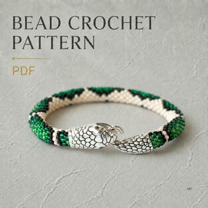 Könnte beinhalten: Ein Perlenhäkelmuster als PDF mit einem Armband, das einen silbernen Verschluss in Schlangenform hat. Das Armband zeigt ein geometrisches Muster aus cremefarbenen, schwarzen und grünen Perlen. Der Text BEAD CROCHET PATTERN PDF steht oben.