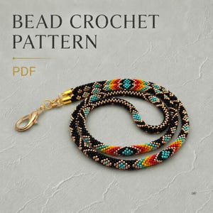 May include: A bead crochet pattern PDF featuring a coiled rope necklace made of small black, turquoise, orange, and yellow beads. The necklace has a gold-tone metal lobster clasp attached to one end, showcasing a repeating geometric pattern.