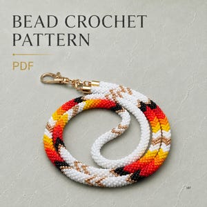 Peut inclure: Un modèle de crochet de perles en PDF présentant un cordon composé de perles blanches, jaunes, orange, rouges et noires disposées en un motif géométrique en chevron. Le cordon inclut un fermoir mousqueton et des embouts dorés.
