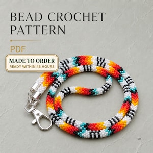 Peut inclure: Un cordon en crochet perlé présentant un motif géométrique répétitif avec des perles rouges, orange, jaunes, blanches, noires et turquoise. Le cordon circulaire est doté d'embouts en métal argenté et d'un fermoir mousqueton assorti.
