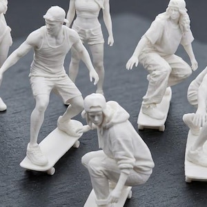 Peut inclure: Un ensemble de six petites figurines blanches représentant des personnes en tenue décontractée. Quatre personnages sont dans des poses dynamiques sur des skateboards, tandis que deux sont debout. Chaque figurine porte une casquette et des vêtements.