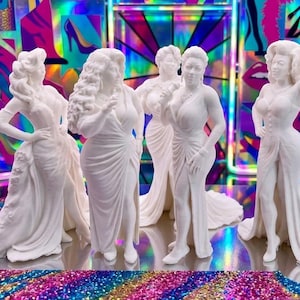 May include: Five white statues of women in elegant gowns, arranged on a reflective surface with a rainbow glitter effect. The background features colorful abstract art with high heels and lips.