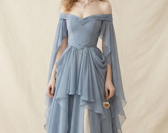 Könnte beinhalten: Ein staubblaues, bodenlanges Kleid mit schulterfreiem Ausschnitt und drapiertem Stoff, langen, fließenden Ärmeln, einem taillierten Oberteil mit überkreuztem Taillendetail und einem mehrlagigen, plissierten Rock, der einen helleren Stoff darunter zeigt.