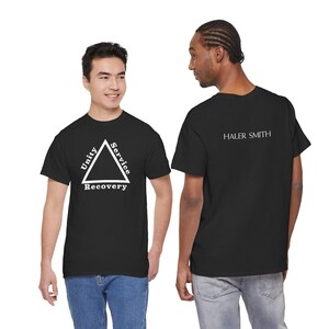 May include: Black t-shirts with white text. One shirt features a triangle with "Unity, Service, Recovery" inside. The other shirt has "HALER SMITH" printed on the back. Both shirts are worn by people.