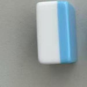 May include: A rectangular block with rounded corners, featuring a smooth, glossy finish. The object is divided vertically into two distinct colour sections, with a solid white panel on the left side and a solid light blue panel on the right side.