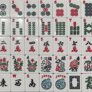 Pode incluir: Um conjunto completo de pe&ccedil;as de Mahjong brancas, apresentando v&aacute;rios s&iacute;mbolos, n&uacute;meros e caracteres em vermelho e verde. As pe&ccedil;as est&atilde;o dispostas em uma grade, mostrando os diversos desenhos e s&iacute;mbolos usados no jogo.