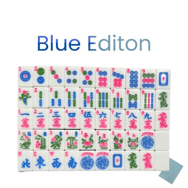 May include: A complete set of white Mahjong tiles with blue, pink, and green markings. The tiles feature Chinese characters and symbols, with the text "Blue Editon" in blue above the tiles. The set includes Jokers and directional tiles.