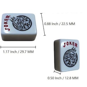 May include: White Mahjong tile with the word "JOKER" in red and a black and white graphic. The tile measures 1.17 inches (29.7 mm) long, 0.88 inches (22.5 mm) high, and 0.50 inches (12.8 mm) thick. The tile is a game piece.