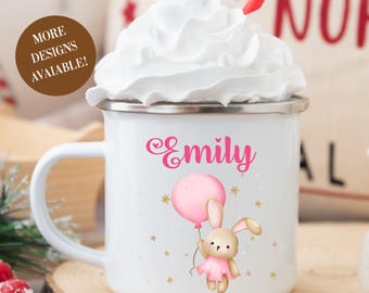 May include: White enamel mug with a silver rim, featuring the name "Emily" in pink script, a cartoon bunny holding a pink balloon, and gold stars. The mug is filled with whipped cream and has a red and white striped straw.