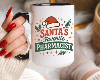 May include: White ceramic mug with a black handle and rim, displaying the text "Santa's Favorite Pharmacist" in red, green, and orange. The design includes a Santa hat, stars, and festive accents, ideal for a pharmacist during the Christmas season.