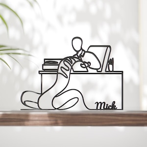 Peut inclure: Sculpture de bureau en métal noir représentant une personne à un bureau avec un ordinateur et des livres. La sculpture a un design minimaliste en ligne continue. Le nom "Mick" est écrit en cursive sur le bureau.