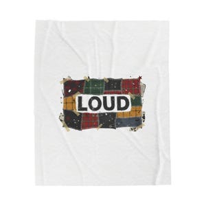 Può includere: Una coperta bianca con un design a toppa rettangolare. La toppa è composta da vari quadrati di tessuto nei colori rosso, verde e nero, con la parola "LOUD" a lettere bianche. La toppa è fissata alla coperta con del nastro adesivo.