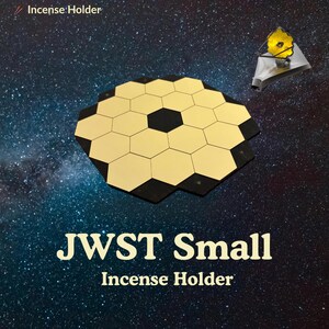 May include: A gold and black hexagonal incense holder with the text "JWST Small Incense Holder" against a starry background. A small, gold-colored model of the James Webb Space Telescope is also present.