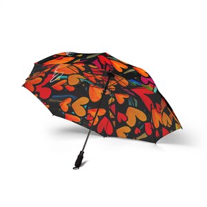 May include: Open umbrella with a black background and a vibrant pattern of orange, red, and yellow hearts. The umbrella has a black handle and a curved design. The overall theme is love and romance.