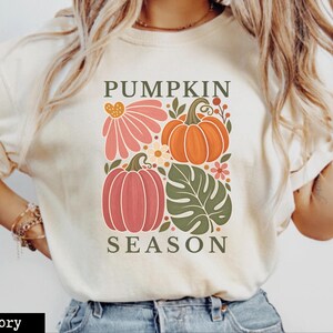 Ivory Pumpkin Season Comfort Colors shirt with retro orange and pink pumpkins, coral flowers, olive green leaves and boho botanical design. Cute fall pumpkin T-shirt, Thanksgiving tee, autumn gift for her and harvest season graphic shirt.