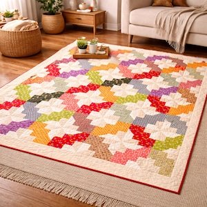 May include: A rectangular patchwork quilt featuring a repeating pinwheel pattern in various colors including red, orange, yellow, green, purple, and cream. The quilt has a cream-colored border and is finished with a thin red edge trim.
