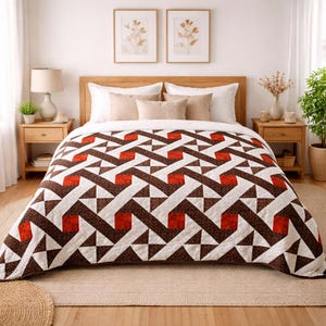 May include: A geometric patterned quilt in shades of brown, white, and red covers a bed. The quilt features a repeating design of triangles and squares. The bed is made up with pillows and a wooden headboard. Two framed botanical prints hang on the wall.