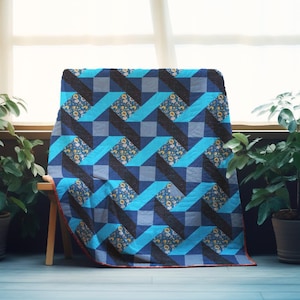 May include: A handmade quilt with a geometric design in shades of blue, gray, and black. The quilt features a repeating pattern of angled lines and squares, with sections of floral fabric. The quilt is draped over a wooden chair.
