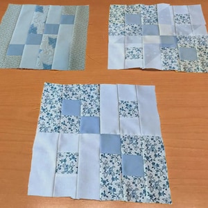 Puede incluir: Tres cuadrados de patchwork en varias etapas de finalización. Cada cuadrado presenta una combinación de telas azul claro, blancas y con estampados florales. Los cuadrados están dispuestos sobre una superficie de madera, mostrando el proceso de acolchado.