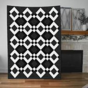 May include: A rectangular quilt featuring a repeating geometric pattern of large black diamonds and smaller white diamond outlines. The design is composed of alternating dark charcoal gray and solid black fabric squares arranged in a grid.
